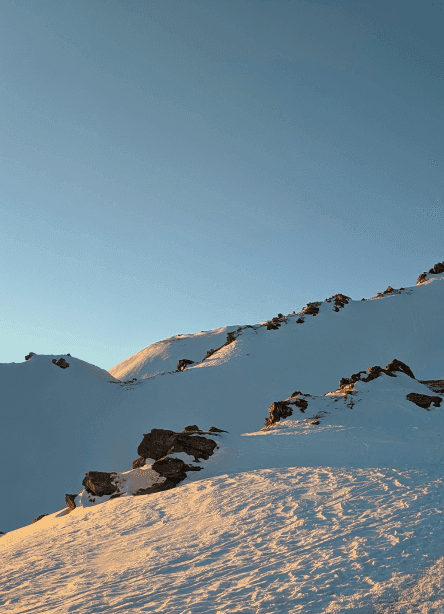 Sunlight falling across a snowy mountain slope beneath a blue sky.